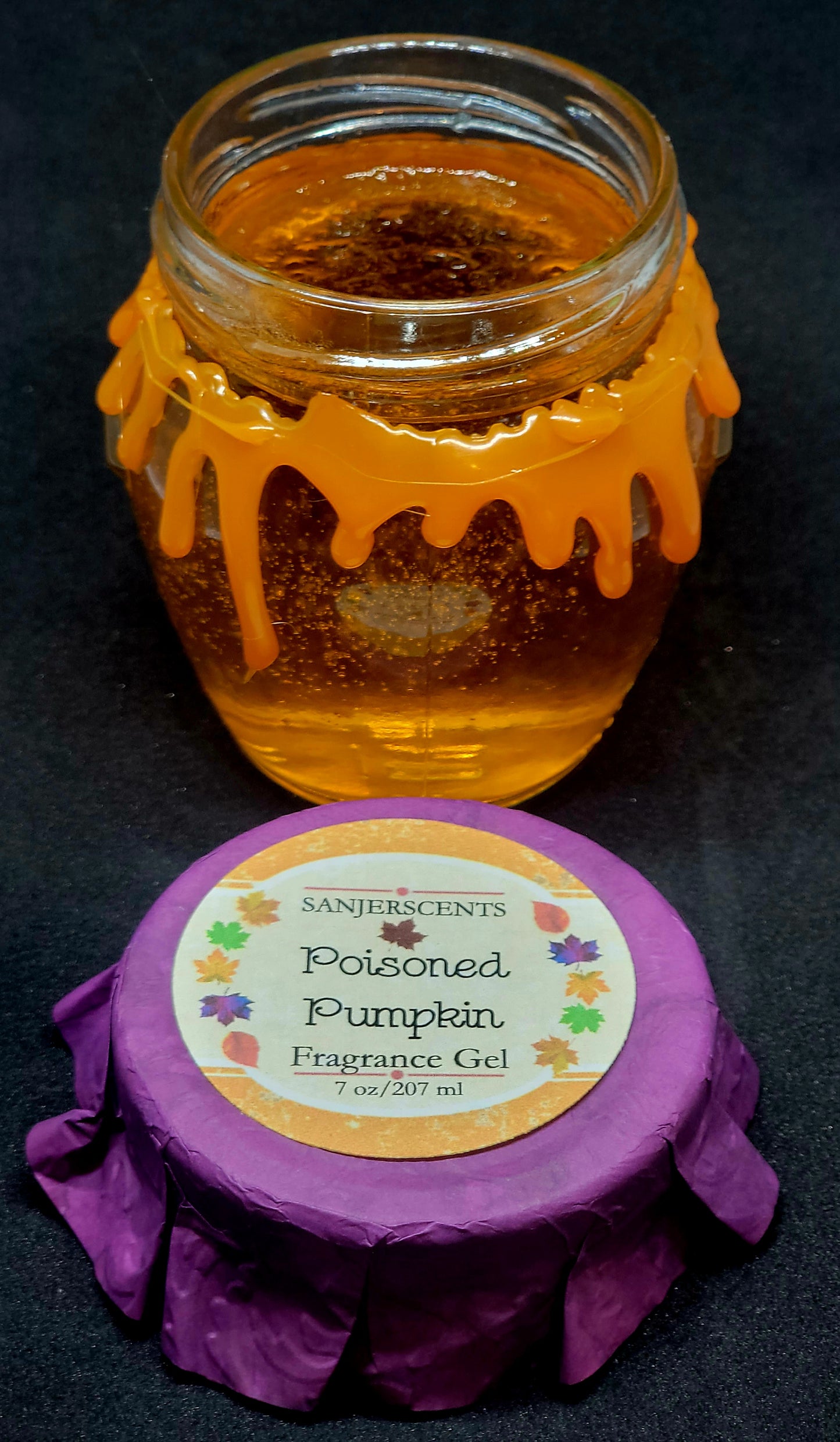 7 oz glass honeypot jar with orange Poisoned Pumpkin fragrance gel. Metal screw top lid with purple cover